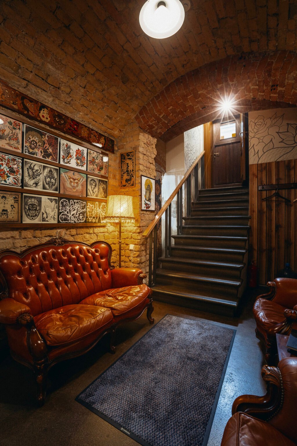 The studio's waiting area with leather sofas, framed drawings and a staircase